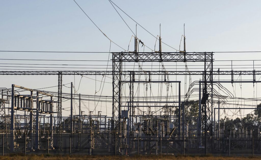 Home High-voltage electrical substation with steel structures and power lines at dawn.
