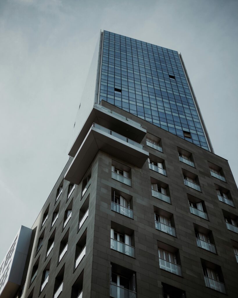 Home High angle view of a modern skyscraper against a cloudy sky, featuring glass and concrete architecture.