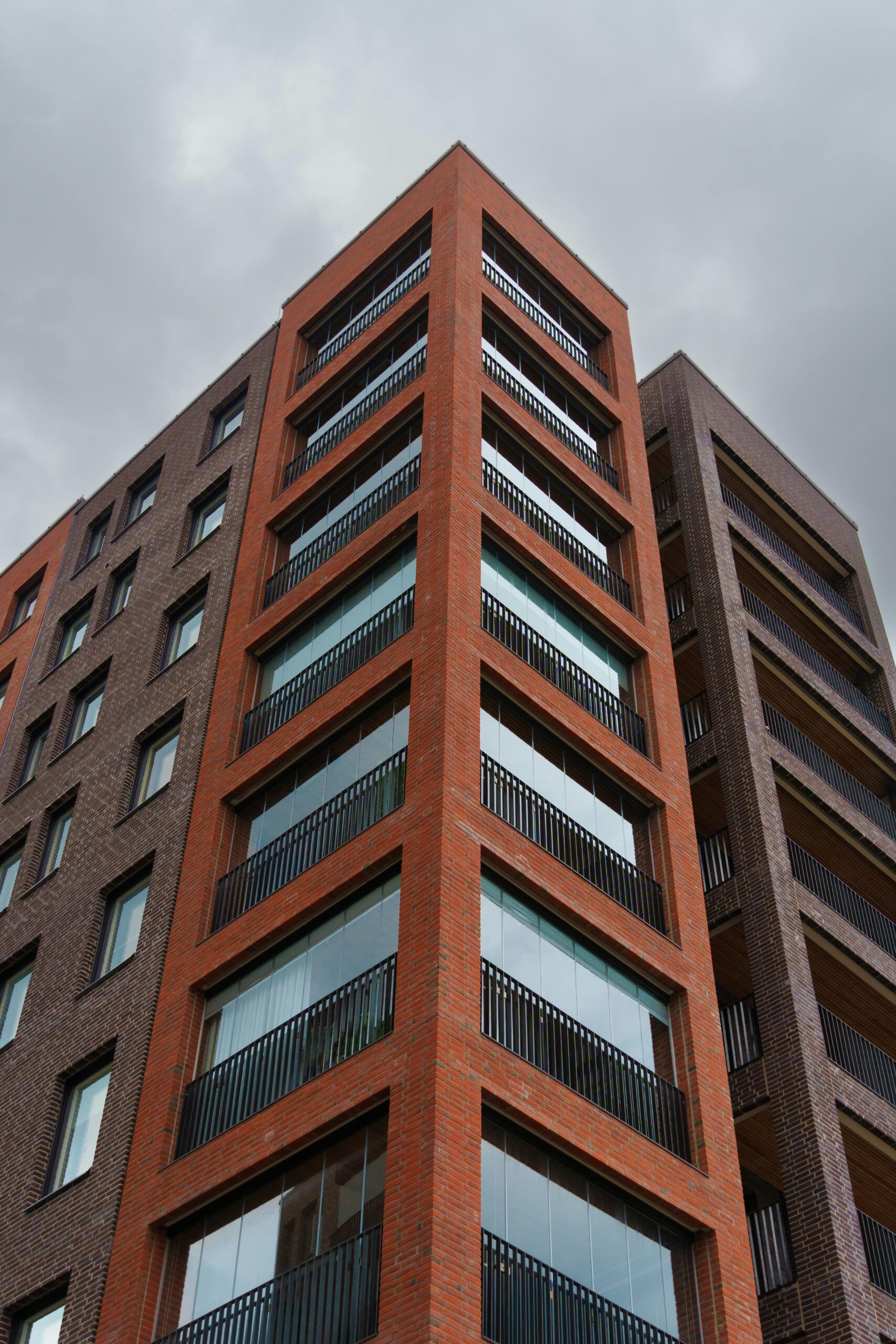 Low angle view of a modern apartment building against a grey sky.